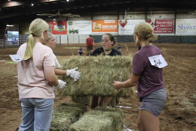 Bethel FFA students Lilly Ingmire, Quinn Carpenter, Bailey Murray and Rianne Tinsley complete their relay race at the Farmhand Olympics by stacking hay bales on Sept. 6. Countywide & Sun/Natasha Dunagan