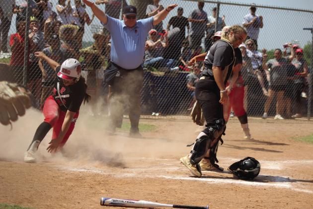 North Rock Creek’s Morgan Campbell jumps up after sliding across home, as Tecumseh catcher Alyssa Norton recovers her helmet and the umpire declares Campbell safe, during the Class 5A Slow Pitch State Semifinals.