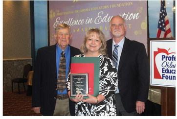 Tecumseh art teacher Jennifer Cox poses after receiving the Professional Oklahoma Educators Foundation High School Educator Merit Award on April 19. Shown with her are, left, Bill Bentley, Chairman of the POE Foundation Board, and right, Tony Hutchinson, President of the POE Board of Directors. Photo provided.