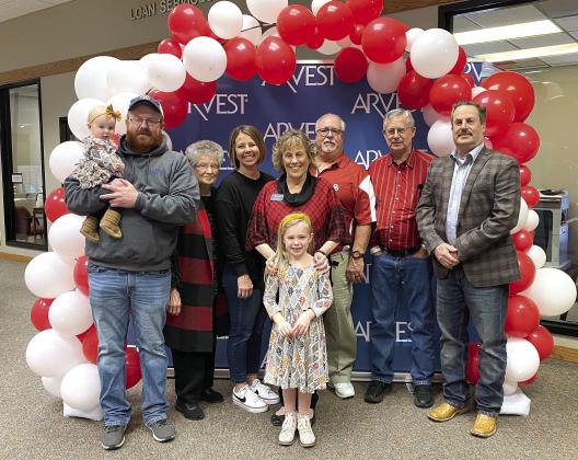 Kim Rawls, center, poses with her family during her retirement reception at Arvest Bank on Dec. 30. Shown are, from left, Zachary Rawls holding Ruby Rawls; Wanda Hulin, Amanda Rawls; Kim Rawls with Ellison Rawls; Michael Rawls; Mike Hulin; and Russell Hulin. Photo provided.